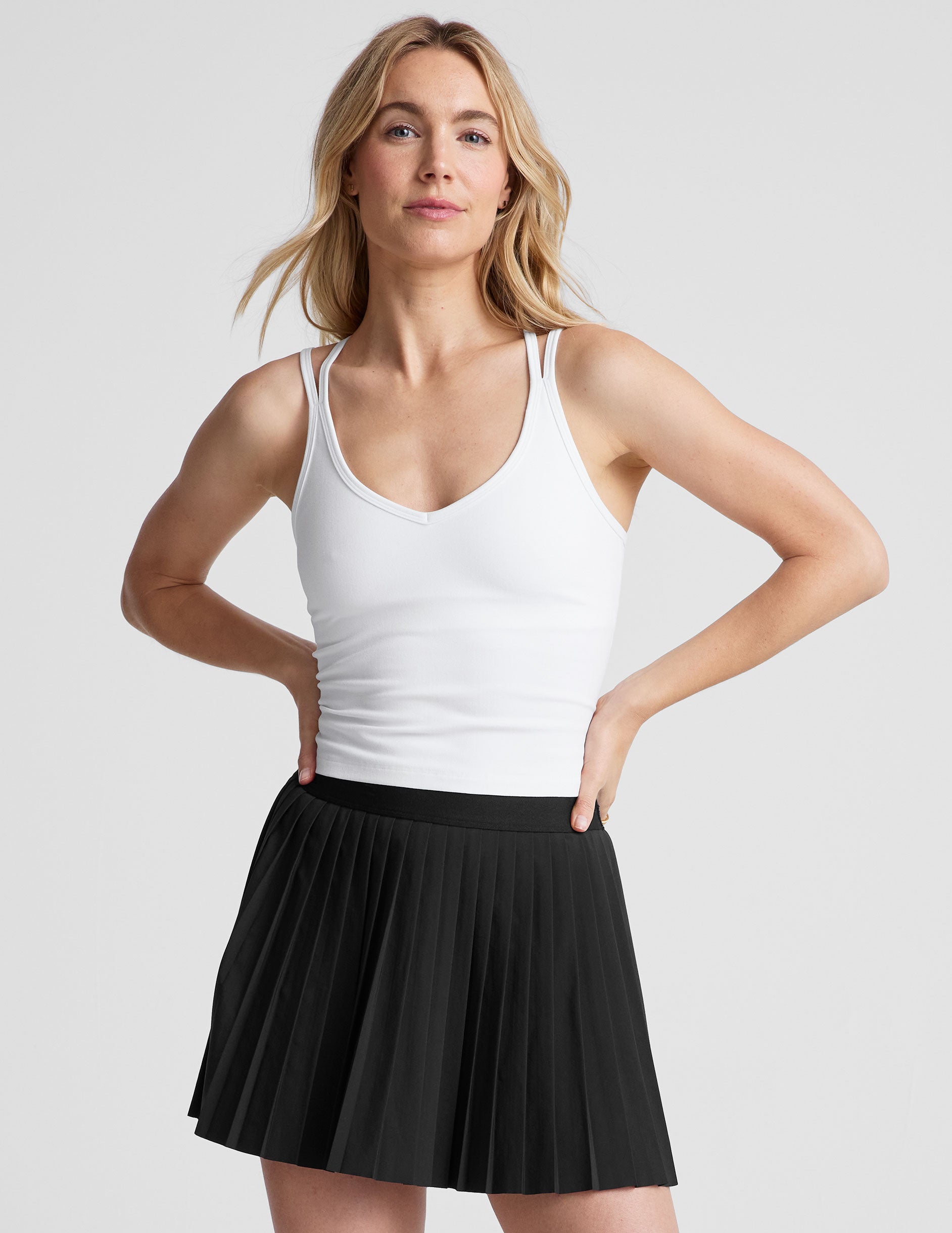 white waist length, V neckline tank top with a self shelf bra and criss-cross strap back detail.